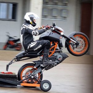 Motorradfaher übt einen Wheelie auf einem Motorrad mit Sondervorrichtung